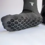 Medias deportivas de caña media color fucsia, con suela antideslizante de puntos negros y logo de la marca estampado en la parte superior.
