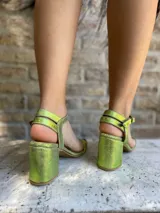 Sandalias de cuero color verde con acabado brillante, taco cuadrado medio y diseño de doble tira en el talón con cierre de hebilla ajustable.