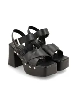 Sandalia de taco alto con plataforma, color negro, con tiras cruzadas en la parte delantera y tira ajustable en el talón. Cuenta con detalles de tachas metálicas en los laterales de la plataforma.