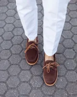 Zapato náutico de cuero gamuzado color marrón chocolate, con cordones y suela plana.