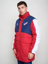 Parka larga de abrigo Umbro del Club Nacional de Football, con diseño tricolor en rojo, azul y blanco. Presenta cuello alto, cierre frontal con solapa, bolsillos con cierre en el pecho y logo de la marca junto al escudo del club.