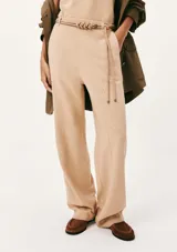Pantalón recto color beige de tiro medio, con bolsillos laterales y un cinturón fino integrado con detalle de nudos en la parte delantera.