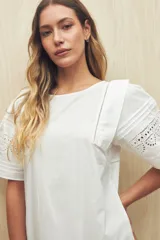 Vestido corto blanco con cuello redondo, mangas cortas amplias y calados geométricos en el ruedo de las mangas.