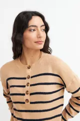 Sweater de punto color crema con rayas horizontales azul marino, cuello redondo y media botonadura frontal con botones marrones.