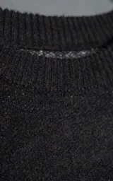 Sweater de punto negro con textura suave, cuello redondo y diseño oversize. Presenta un bordado frontal con la frase 'art SUPPORT' en letras rojas y blancas, y un pequeño detalle de tijeras bordado en la nuca.