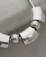 Collar de acero de cadena tipo serpiente con diseño frontal compuesto por tres piezas cilíndricas intercaladas por dos esferas metálicas.