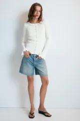 Chaqueta de punto rib color blanco, con cuello redondo, manga larga con acabado ondulado en los puños y cierre frontal con botones.