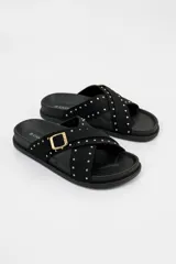 Sandalias negras de tiras cruzadas decoradas con tachas doradas, con hebilla lateral ajustable y suela anatómica.