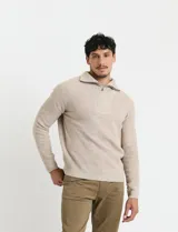 Remera de punto inglés de manga larga color beige, con cuello alto y medio cierre metálico plateado. Presenta diseño de canalé en toda la prenda.