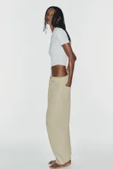 Jeans de tiro medio y corte barrel con diseño de perneras curvadas, tiro medio, trabillas para cinturón y cinco bolsillos. Presenta lavado clásico y costuras pespunteadas decorativas en la parte delantera.