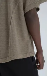 Remera de manga corta y cuello redondo, color verde militar, confeccionada en algodón premium con textura de tejido a rombos. Presenta un calce regular con recortes deshilachados en los hombros.