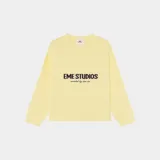 Suéter de punto grueso color amarillo, con corte cuadrado y ligeramente corto. Presenta cuello redondo, mangas largas con puños ajustados y el logo de la marca Eme Studios junto a la frase 'curated by ben ice' en jacquard oscuro en el centro del pecho.