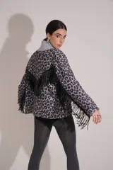 Saco de tejido grueso con estampado de leopardo en tonos gris y negro, cuello alto en color gris liso y flecos negros aplicados en forma de 'V' en la espalda y a lo largo de las mangas.