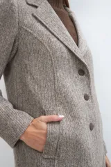 Saco corto entallado de lana fina, con cuello solapa, manga larga y cierre frontal con botones. Presenta un diseño clásico con textura de espiga en tonos tierra.
