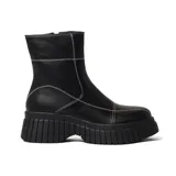 Bota corta negra de cuero sintético con plataforma y suela track. Presenta costuras decorativas en color blanco.