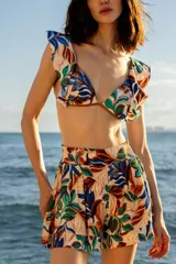 Short de playa con estampado botánico en tonos blanco, azul, verde y marrón. Presenta cintura elástica fruncida y corte estructurado con pliegues frontales.
