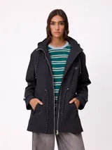 Rompevientos negro con capucha ajustable mediante cordones, cierre frontal de cremallera y ajuste en la cintura con cordón. Presenta logo de la marca bordado en el pecho y puños con detalle de botón.