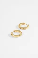 Par de aros tipo argolla de diseño grueso y minimalista, fabricados en acero quirúrgico con acabado plateado brillante.