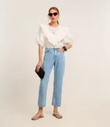 Pantalón recto cropped de jeans celeste con bordados de flores blancas.