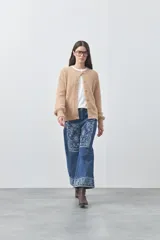 Cardigan de textura suave y efecto fluffy, color beige, con cuello redondo, cierre frontal con botones y puños acanalados.