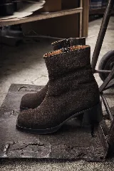 Bota de caña media con punta cuadrada, confeccionada en cuero gamuzado color marrón, con taco bloque y suela de goma negra.