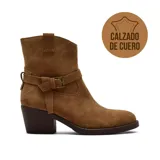 Bota corta de gamuza color marrón, con taco cuadrado de altura media y suela oscura. Presenta una tira decorativa con hebilla metálica ajustable alrededor del tobillo.