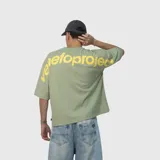 Remera de corte oversize color verde, con estampa tipográfica en color amarillo en la parte superior de la espalda.