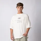 Remera oversize de algodón color crudo, con hombro caído, cuerpo amplio y estampa gráfica frontal en color negro con diseño de libélula y texto.