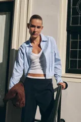 Pantalón de tiro alto color gris oscuro con finas rayas verticales blancas (pinstripe). Posee pernera recta y ancha, y doble cintura elástica con tejido combinado.