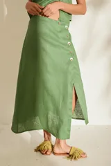 Falda midi verde de lino, con diseño asimétrico, tajito frontal y cierre lateral con botones de madera con ojales bordados.