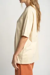 Remera color arena de algodón peinado, corte oversize y manga corta. Estampado pequeño de una concha en el pecho.