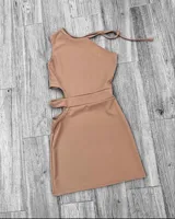 Vestido corto color beige, con un hombro descubierto, corte ajustado y aberturas en la cintura.