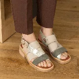 Sandalias bajas de cuero vacuno color beige, con tiras cruzadas en el empeine y ajuste con hebilla lateral.