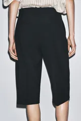 Bermuda larga color marrón oscuro, de tiro medio con cintura con trabillas. Presenta bolsillos laterales ocultos en la costura y detalle de raya planchada. Cierre frontal con cremallera, botón y ganchos metálicos.