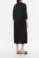 Vestido camisero midi negro de corte holgado, con cuello camisero, mangas 3/4 y cierre frontal con botones.