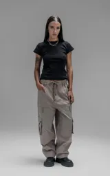 Pantalón cargo de corte oversize y silueta estructurada, confeccionado en microfibra pesada con leve elasticidad. Presenta cintura elástica con cordón de ajuste externo, cierre frontal con botón metálico, bolsillos laterales y bolsillos cargo de gran tamaño con tapa y broches a presión.