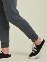 Pantalón tipo babucha de algodón y poliéster, color gris melange, con cintura elástica ajustable mediante cordón, bolsillos laterales y cierres en los tobillos.