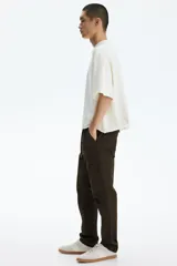 Pantalón cargo slim fit marrón, con cintura elástica ajustable mediante cordón, bolsillos laterales con solapa y costuras decorativas en las rodillas.