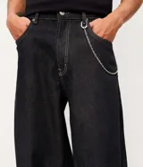 Pantalón de jean estilo baggy balloon, con cintura fija, trabillas para cinturón, cierre tradicional y bolsillos laterales. Presenta un corte amplio y holgado en las piernas.