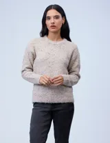Buzo de tejido melange color beige con motas oscuras, cuello redondo y manga larga.