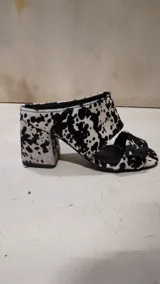Sandalias de tacón alto y ancho, confeccionadas en piel con acabado de pelo y estampado animal print de vaca en tonos marrones y blancos, con tiras anchas en el empeine.