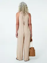 Mono color beige con cuello halter y corte palazzo.