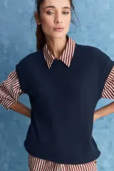 Chaleco de tejido de punto color beige claro, con cuello redondo y diseño de líneas limpias con hombros caídos y terminaciones acanaladas.
