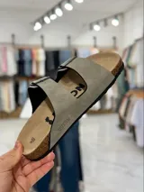 Sandalias de dos tiras negras con hebillas metálicas ajustables, plantilla anatómica y suela plana.