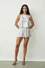 Short de tiro medio en color dorado con acabado metalizado, diseño holgado y bolsillos laterales.