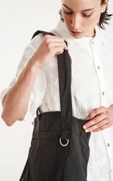 Bolso tipo tote bag de microfibra negra, con correas de hombro y cordón ajustable con tanca. Posee un bolsillo exterior con velcro y un bolsillo interior con cierre.