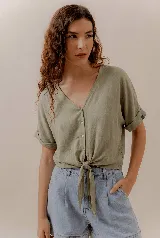Blusa verde oliva de manga corta con puños doblados, escote en V, botones frontales y lazo para anudar en la cintura.