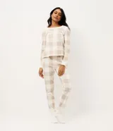 Conjunto de pijama de dos piezas confeccionado en tricot liviano. Incluye una remera de manga larga con escote redondo y un pantalón tipo jogger con cintura elástica y puños ajustados. Presenta un estampado de cuadros en tonos beige y blanco.