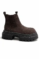 Botas cortas tipo chelsea de gamuza marrón con suela track gruesa y dentada de color negro.