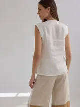 Top sin mangas de lino en color beige con acabado ligeramente brillante, cuello en V y corte recto.